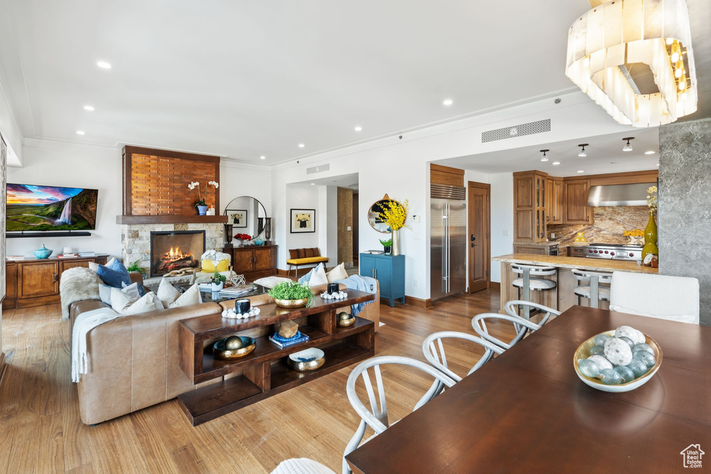 Living area with wood finished floors, ornamental molding, a fireplace, and recessed lighting