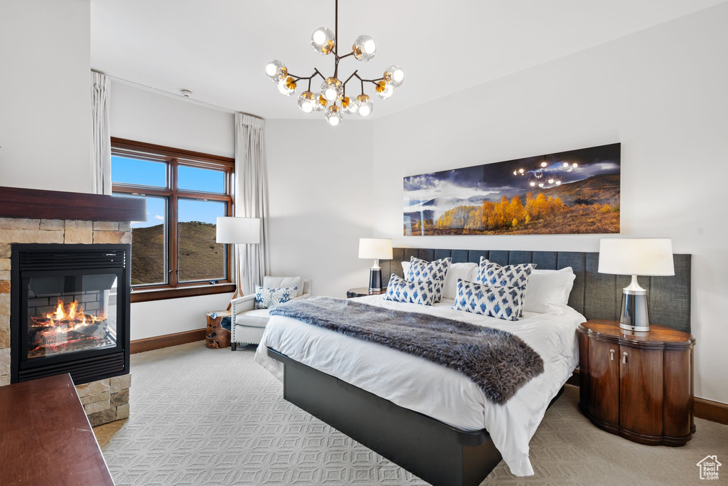 Carpeted bedroom featuring baseboards, a fireplace, and a chandelier