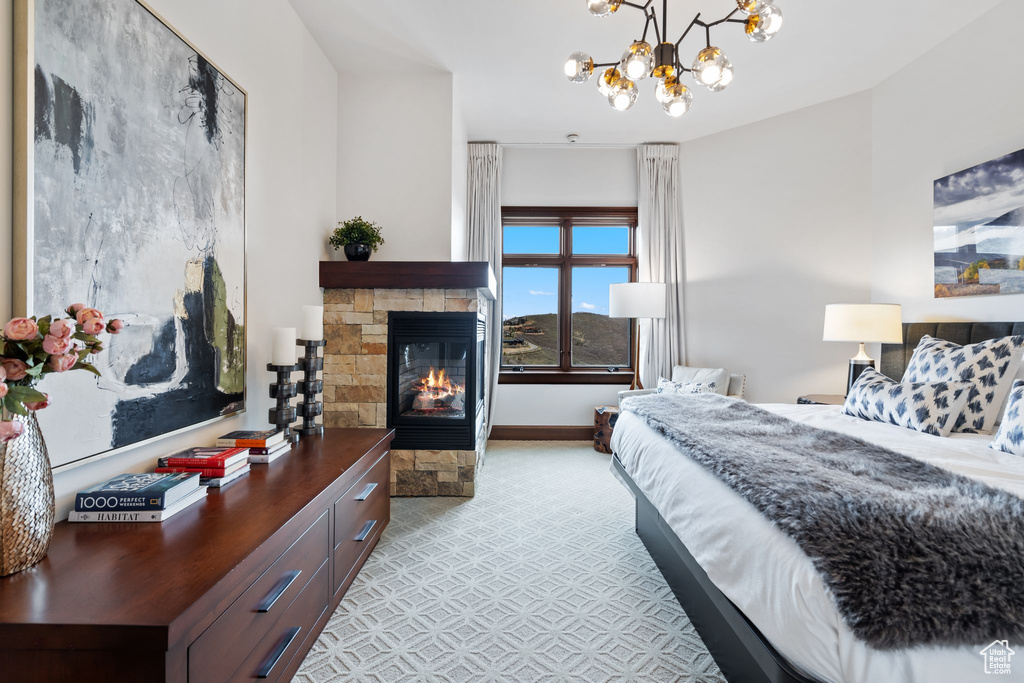 Bedroom with a stone fireplace, a chandelier, and baseboards