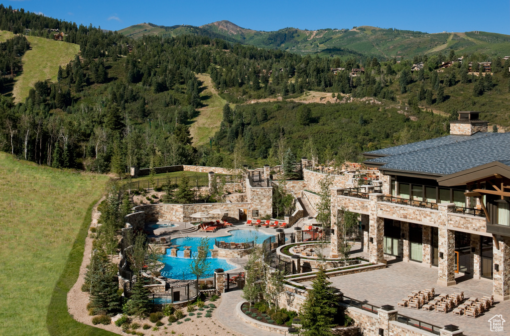 Bird\'s eye view of a mountainous background, a pool, and a forest