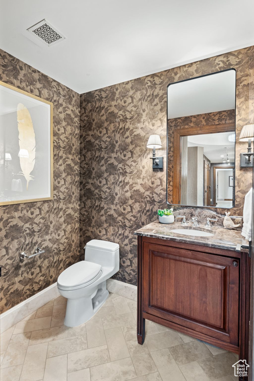 Half bathroom featuring baseboards, toilet, and vanity