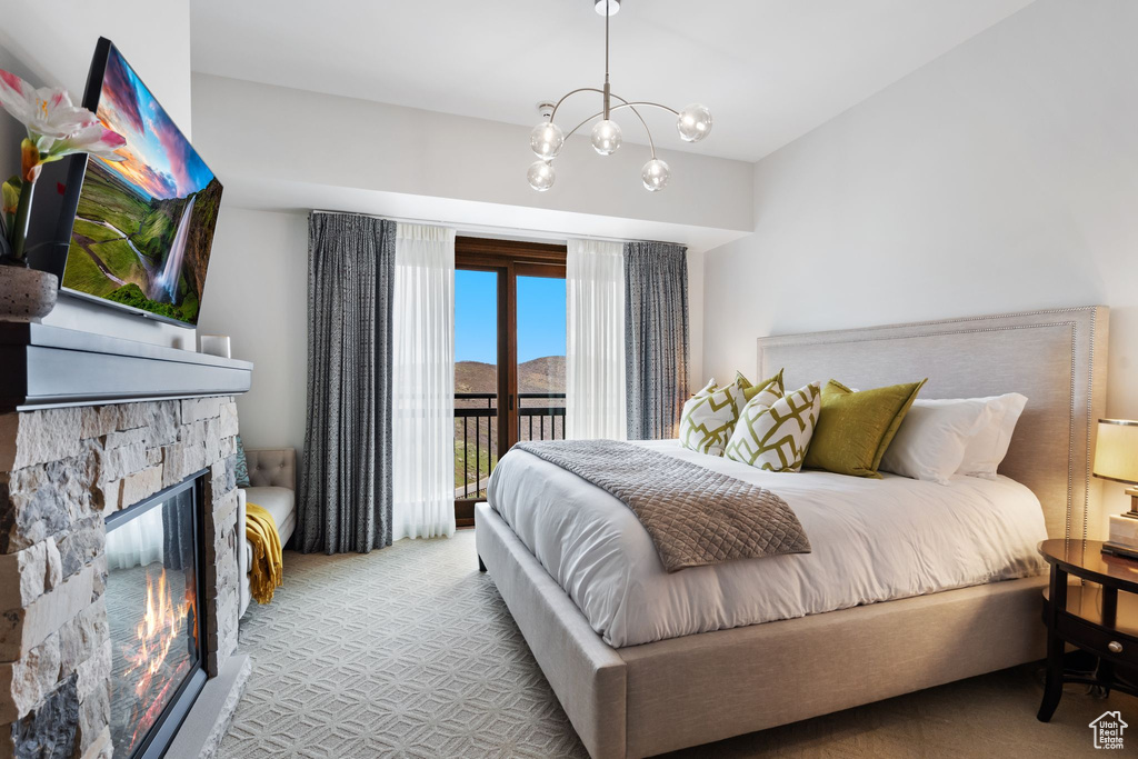 Carpeted bedroom with access to exterior, a chandelier, and a fireplace