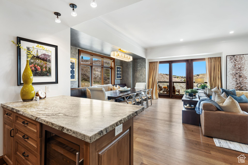 Kitchen with open floor plan, wine cooler, wood finished floors, light countertops, and brown cabinets