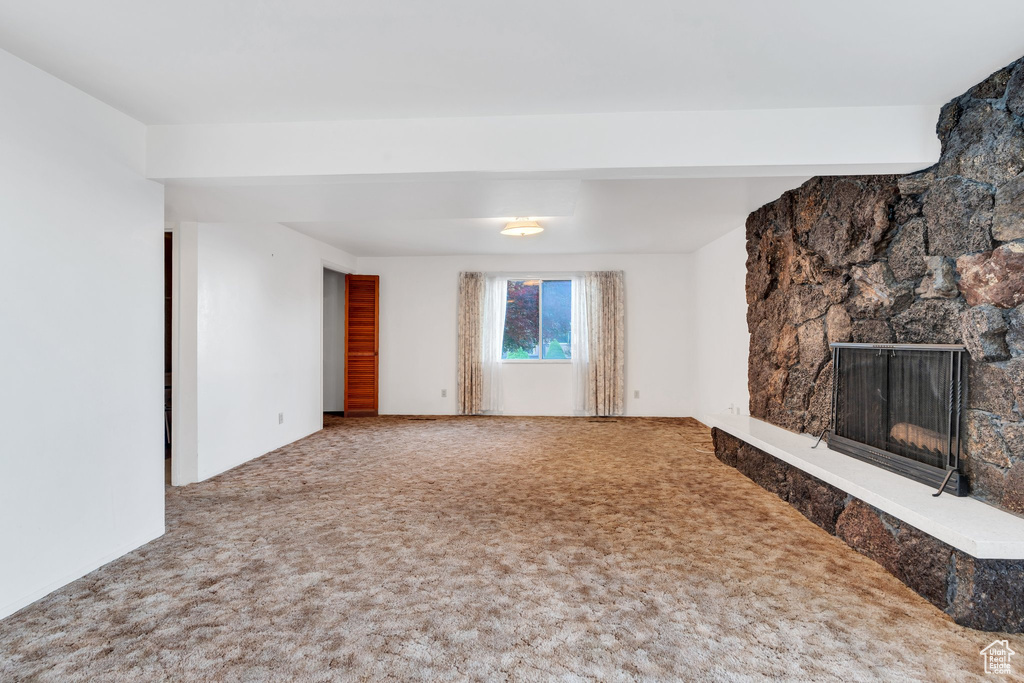 Unfurnished living room featuring carpet flooring and a fireplace