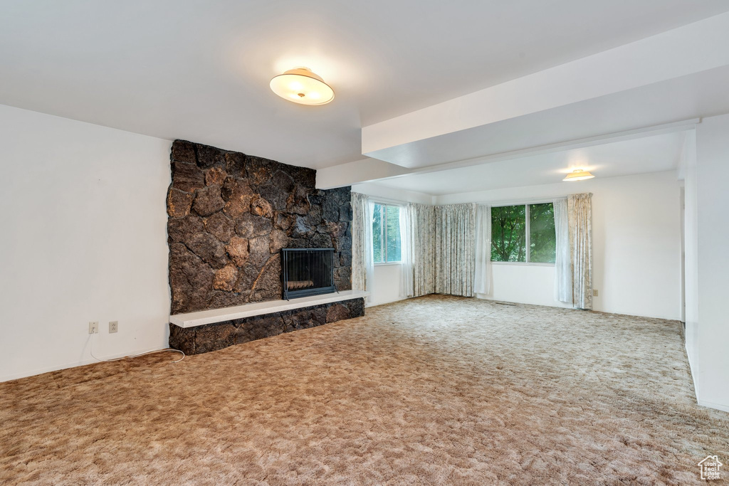 Unfurnished living room with a fireplace and carpet flooring