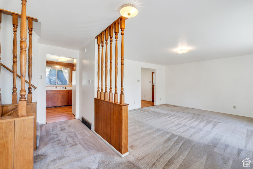 Unfurnished room with carpet, a sink, and stairway