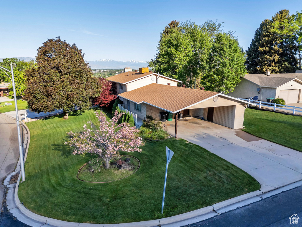 View of front of property featuring concrete driveway, a carport, a shingled roof, and a mountain view