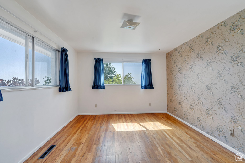 Spare room featuring light wood-style floors, baseboards, and wallpapered walls