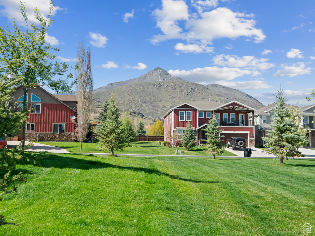 View of green lawn featuring a mountain view and a garage