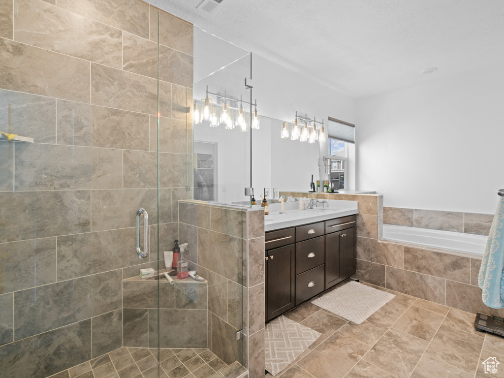 Bathroom featuring a stall shower, vanity, and a garden tub