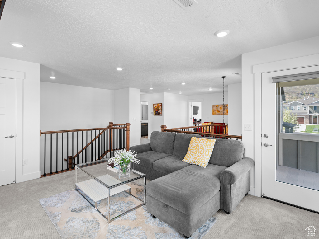 Living room with light carpet, recessed lighting, and a textured ceiling
