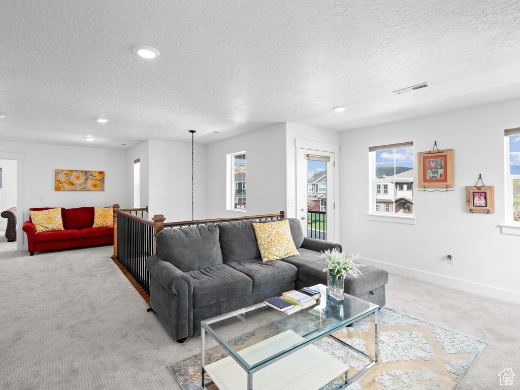 Living area with light colored carpet, a textured ceiling, recessed lighting, and baseboards