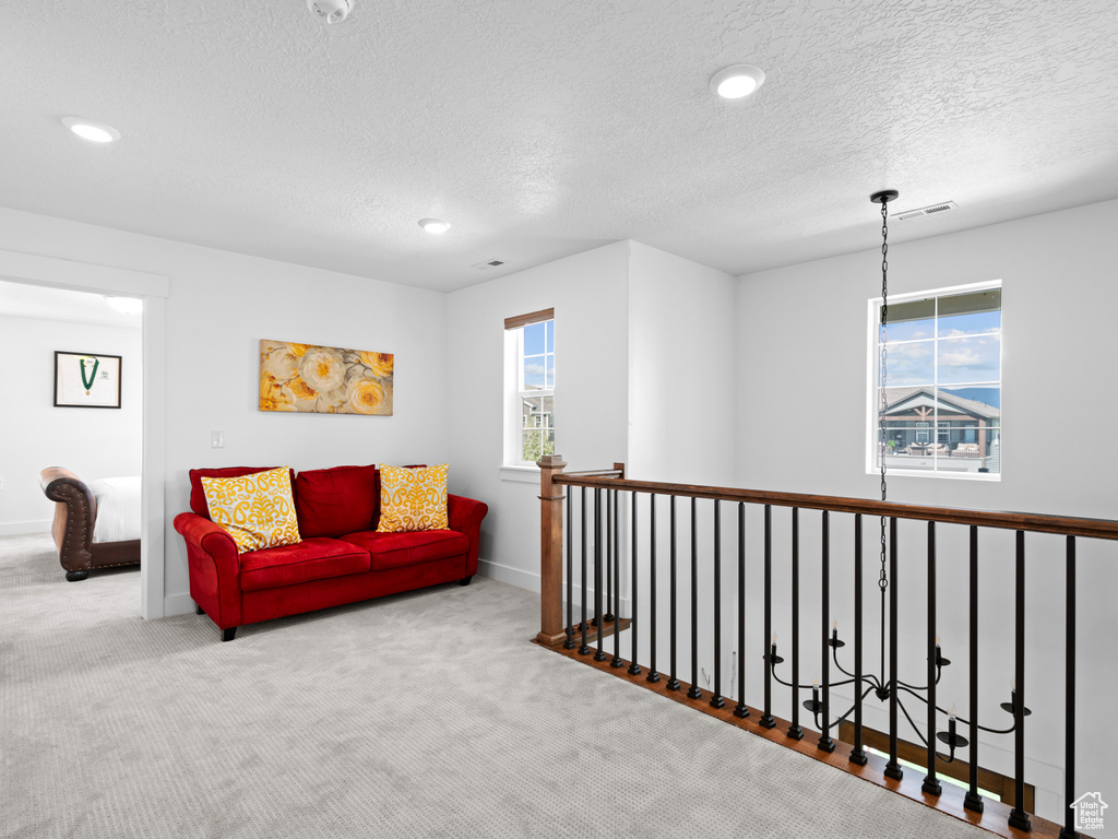 Living area with a textured ceiling, carpet, recessed lighting, baseboards, and an upstairs landing