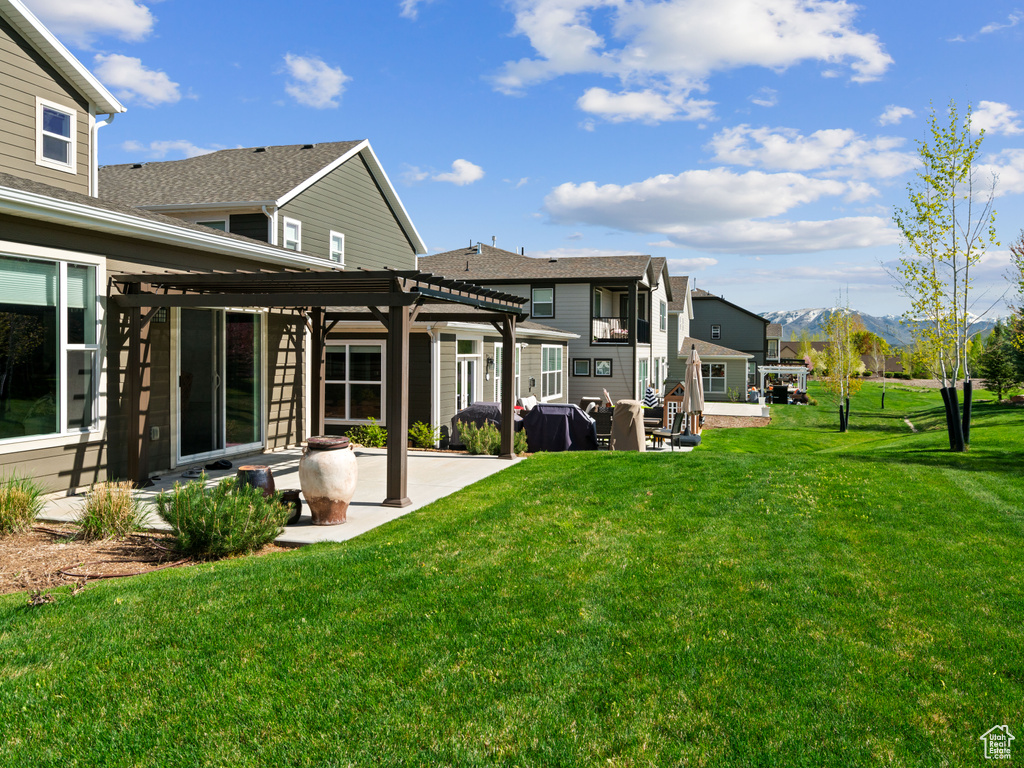 Back of property featuring a pergola, a patio, a mountain view, and a yard