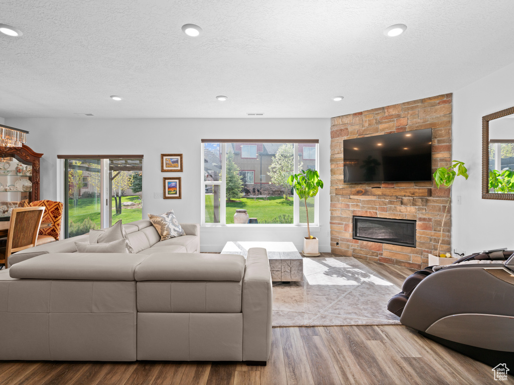 Living area with a fireplace, wood finished floors, plenty of natural light, a textured ceiling, and recessed lighting
