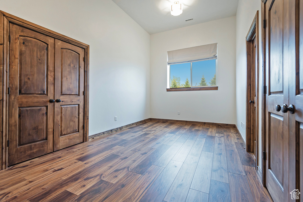 Unfurnished bedroom featuring dark wood finished floors and baseboards