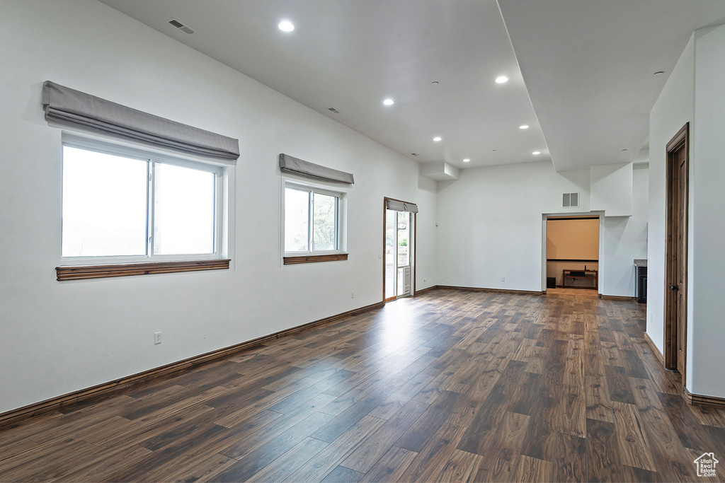 Empty room with dark wood-style flooring, recessed lighting, and baseboards