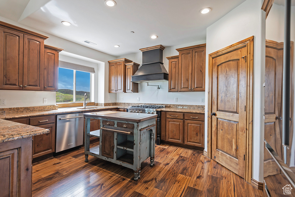 Kitchen featuring stainless steel appliances, custom range hood, a sink, dark wood-style floors, and recessed lighting