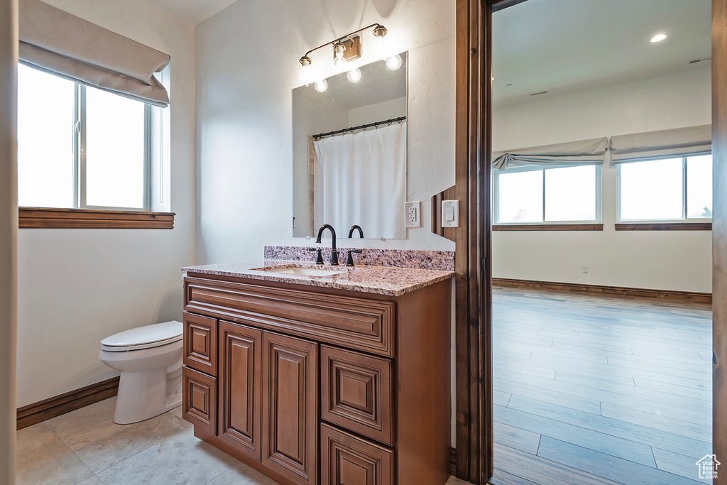 Bathroom with healthy amount of natural light, toilet, vanity, and baseboards
