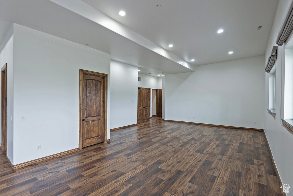 Empty room with dark wood-type flooring, recessed lighting, and baseboards