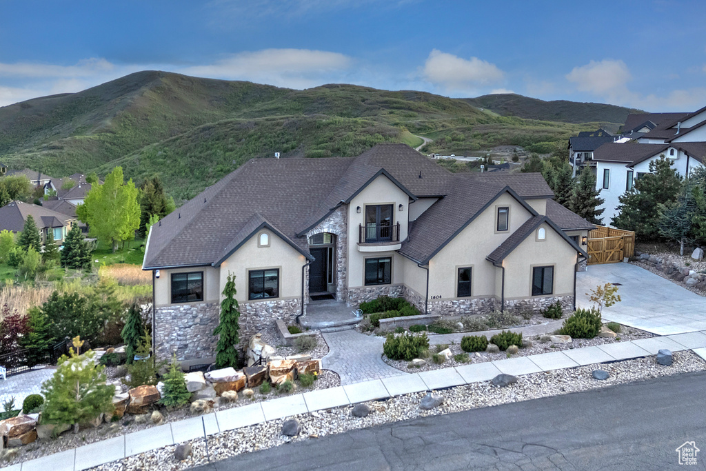 French provincial home featuring stucco siding, stone siding, and a mountain view