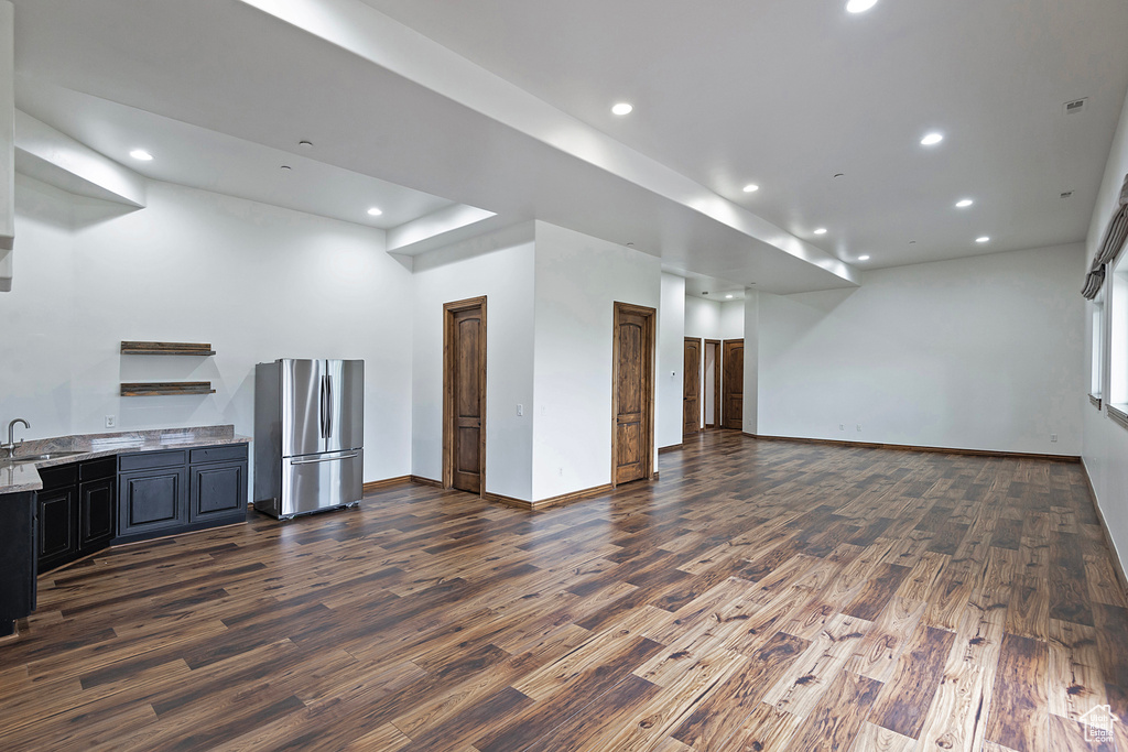 Unfurnished living room with dark wood-type flooring, a sink, recessed lighting, and baseboards