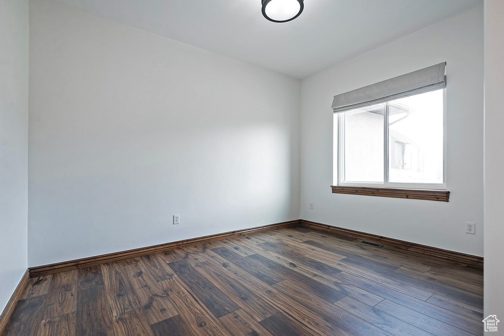 Unfurnished room with dark wood finished floors and baseboards
