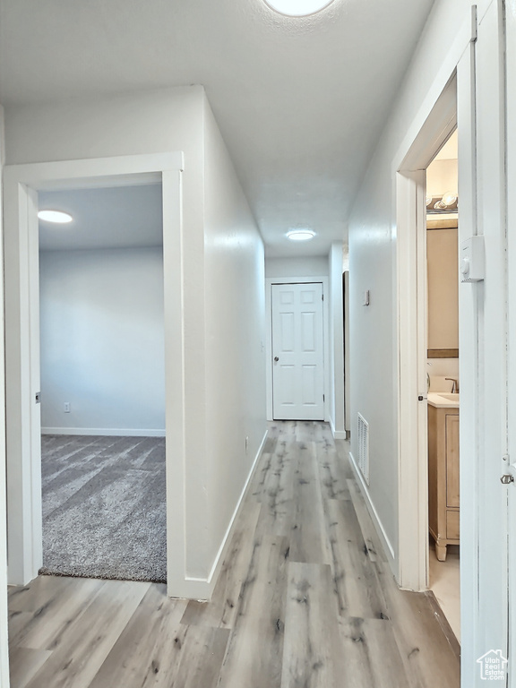 Corridor with wood finished floors, baseboards, and a sink