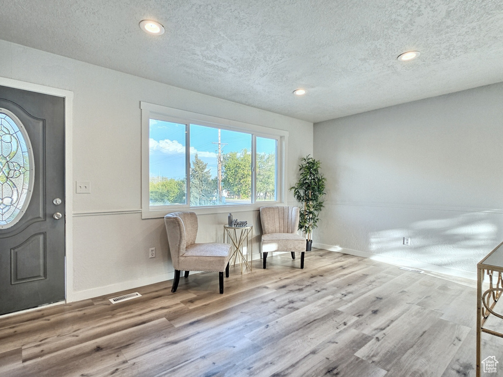 Foyer entrance featuring a textured ceiling, wood finished floors, baseboards, and recessed lighting