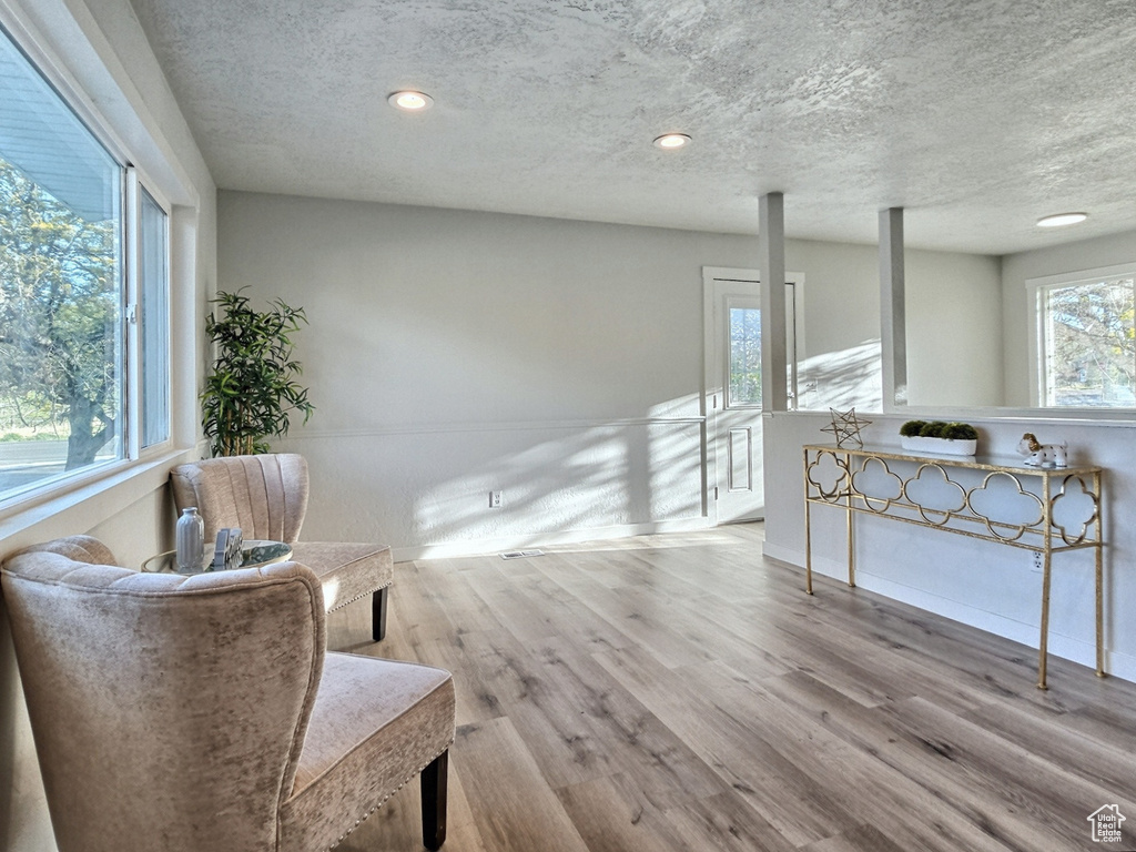 Sitting room featuring wood finished floors, a textured ceiling, recessed lighting, and an upstairs landing