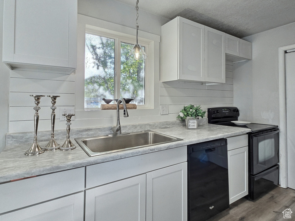 Kitchen with black appliances, a sink, white cabinets, light countertops, and a textured ceiling