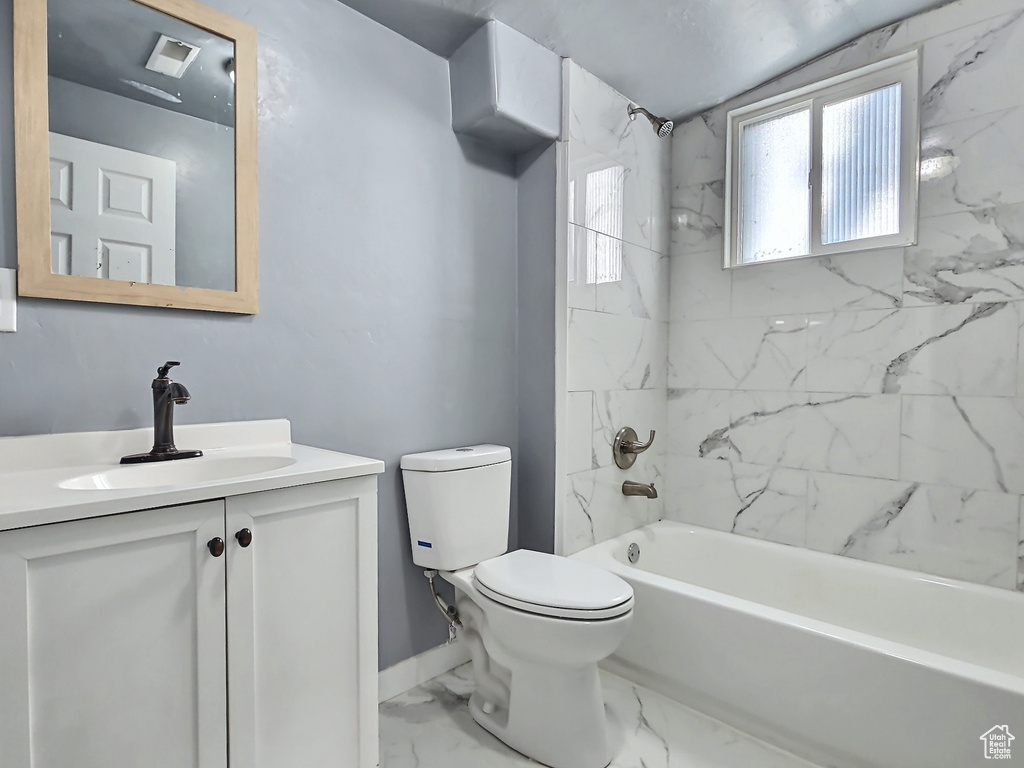 Bathroom featuring toilet, vanity, marble look tiles, bathing tub / shower combination, and baseboards