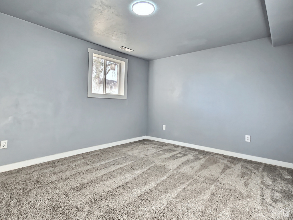 Spare room featuring carpet flooring and baseboards
