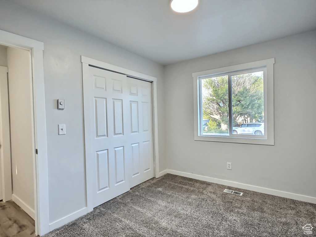 Unfurnished bedroom featuring baseboards, carpet flooring, and a closet