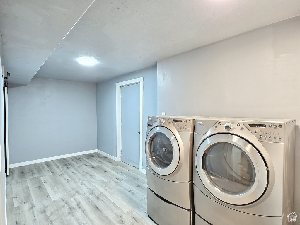 Washroom with independent washer and dryer, light wood-style floors, and baseboards