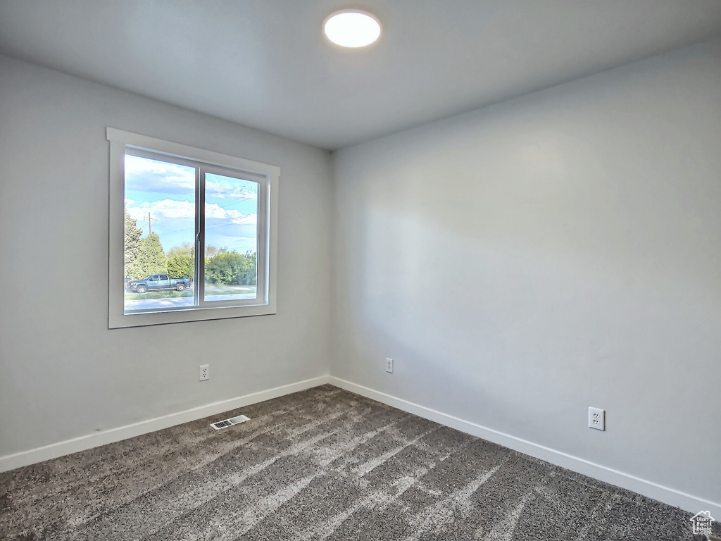 Spare room featuring baseboards and dark carpet