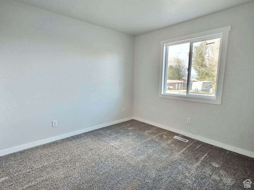 Carpeted spare room featuring baseboards