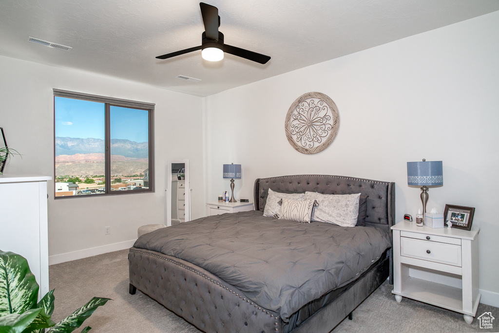 Carpeted bedroom featuring baseboards, a ceiling fan, and a mountain view