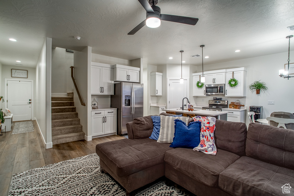 Living area with wood finished floors, ceiling fan, stairs, baseboards, and recessed lighting