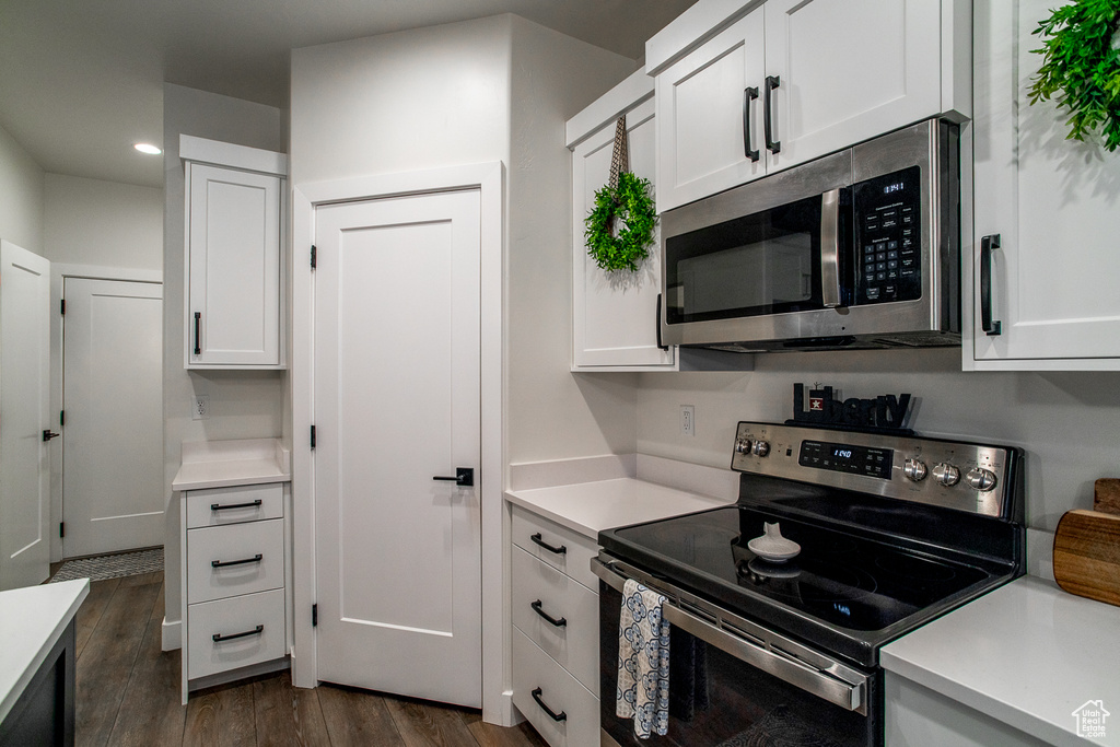 Kitchen featuring appliances with stainless steel finishes, white cabinetry, dark wood finished floors, light countertops, and recessed lighting