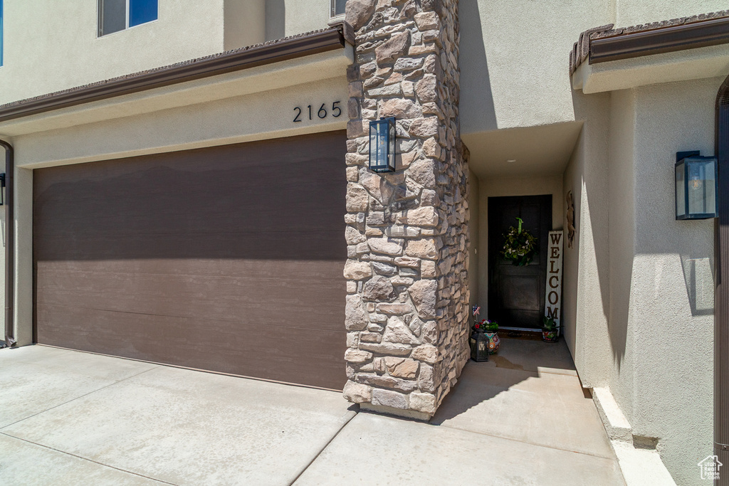 Entrance to property featuring stucco siding, stone siding, and an attached garage