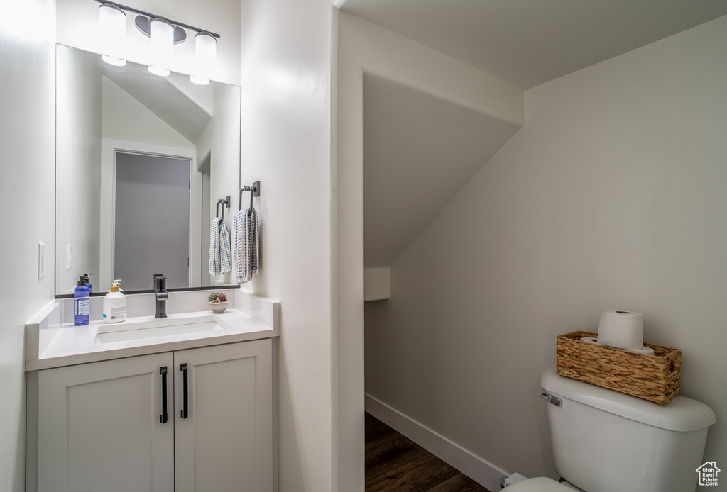 Bathroom featuring toilet, vanity, wood finished floors, and baseboards
