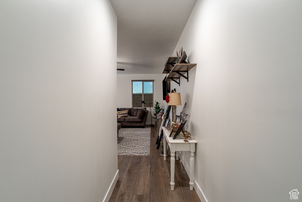 Hallway featuring dark wood-style flooring and baseboards