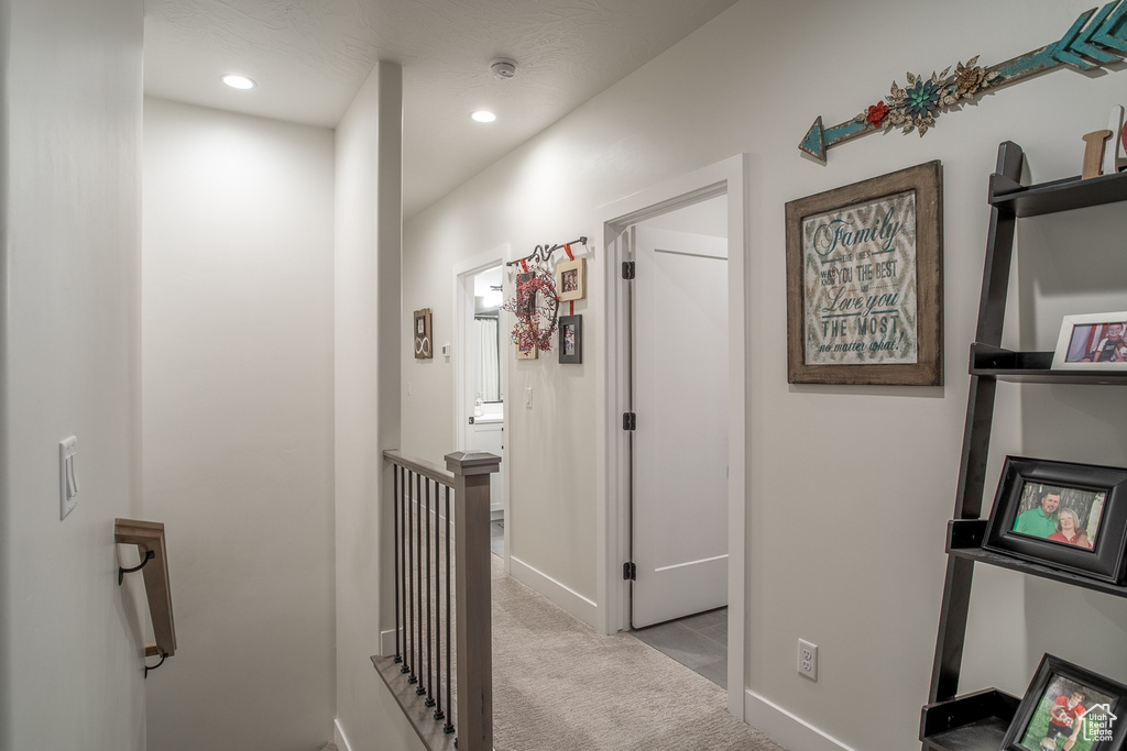 Hallway with carpet flooring, an upstairs landing, baseboards, and recessed lighting