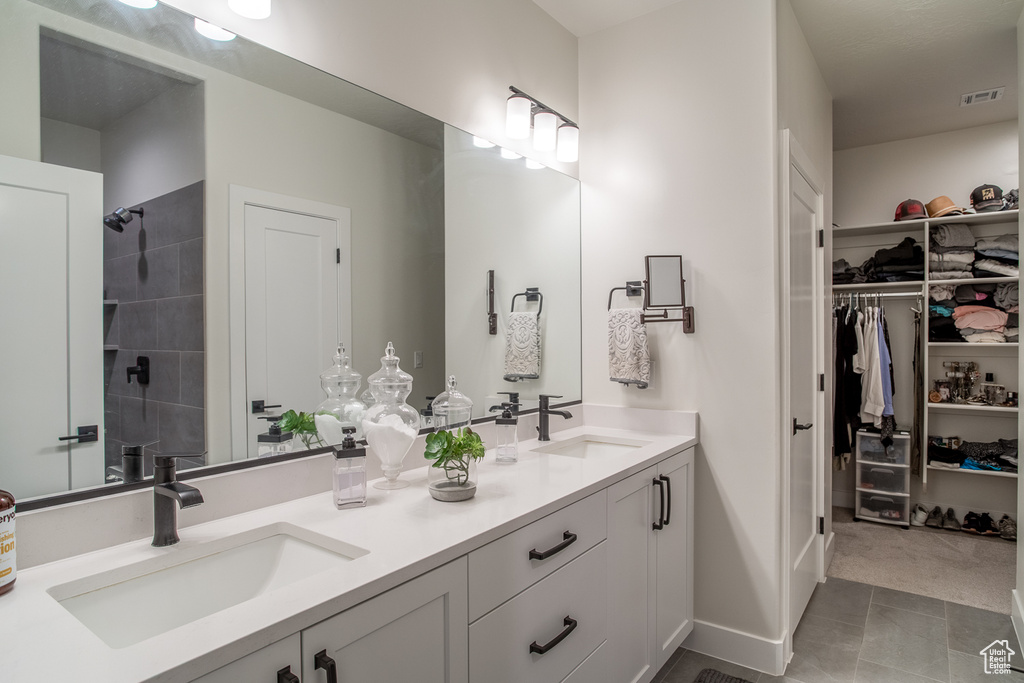 Bathroom featuring double vanity, a walk in closet, and a tile shower