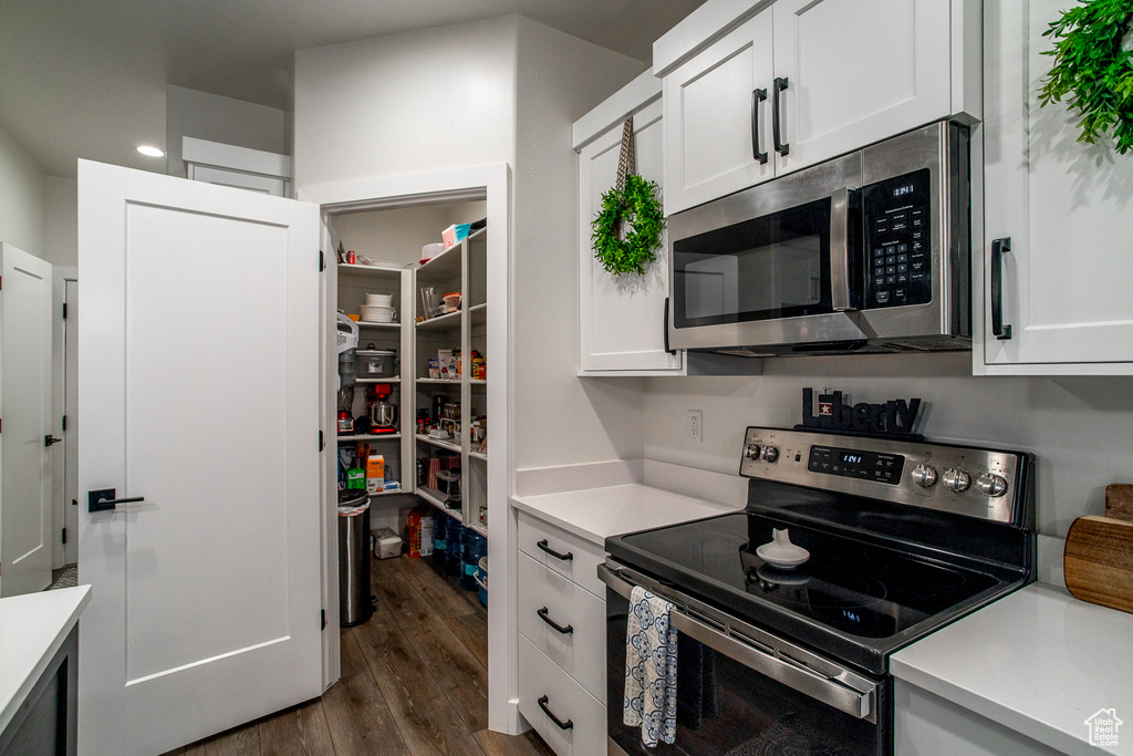 Kitchen featuring appliances with stainless steel finishes, light countertops, dark wood-style floors, and recessed lighting