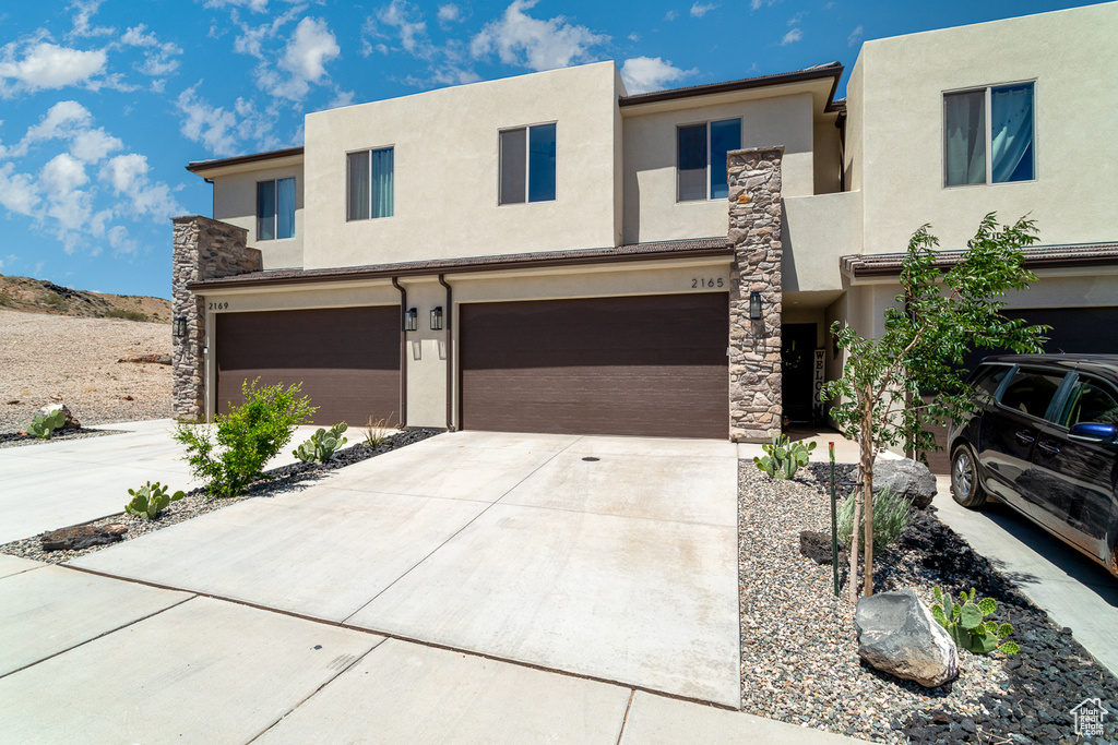 View of front of house featuring stucco siding, an attached garage, and concrete driveway
