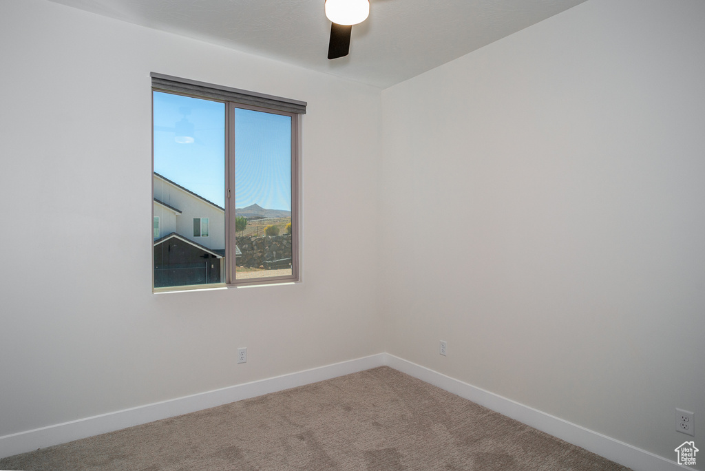 Empty room with baseboards, a ceiling fan, and carpet