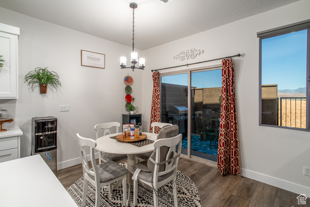 Dining area with dark wood-style floors, baseboards, and a chandelier