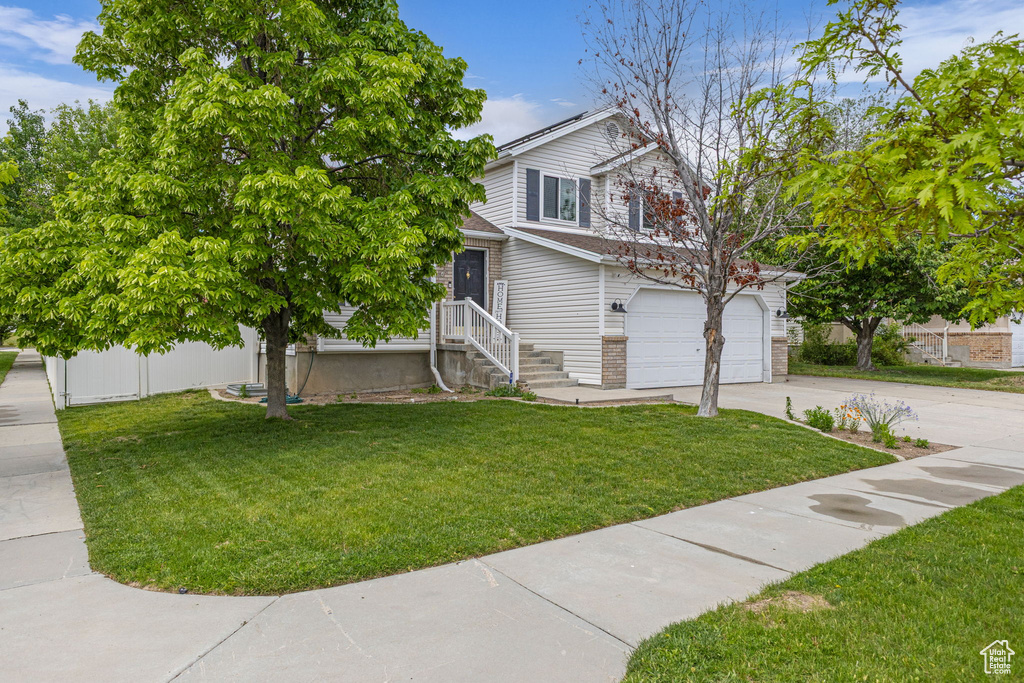 View of front of home featuring driveway, a front yard, and an attached garage